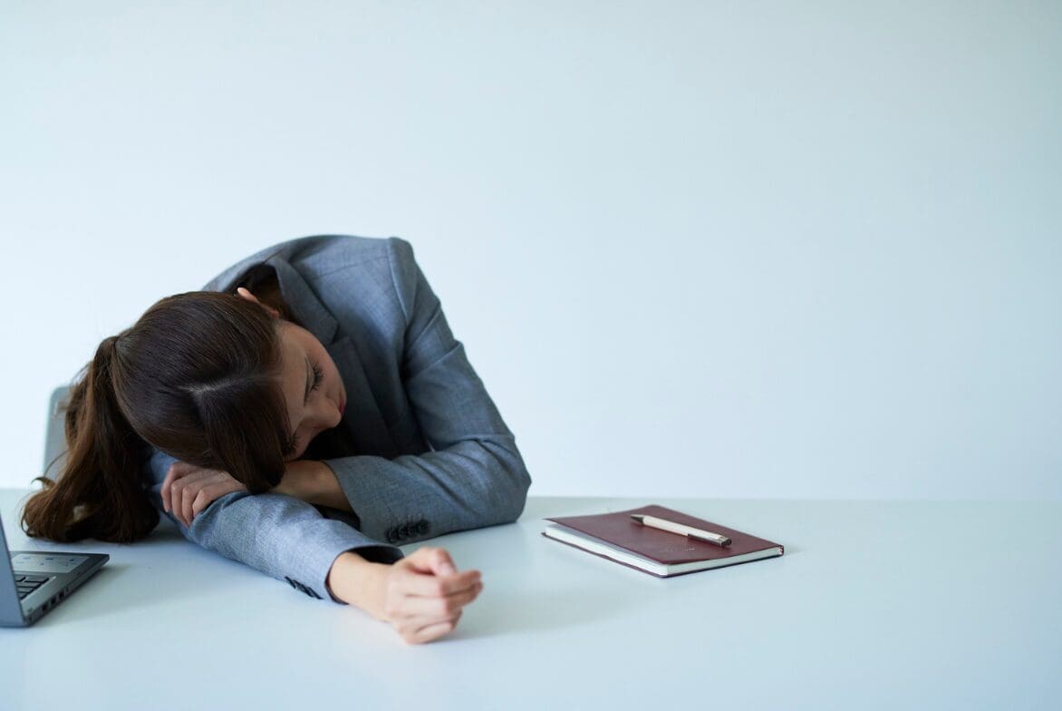 A woman with chronic fatigue lays head down to consider functional medicine